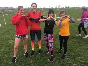 Carlyn and three friends post-run, all making heart shapes with their hands
