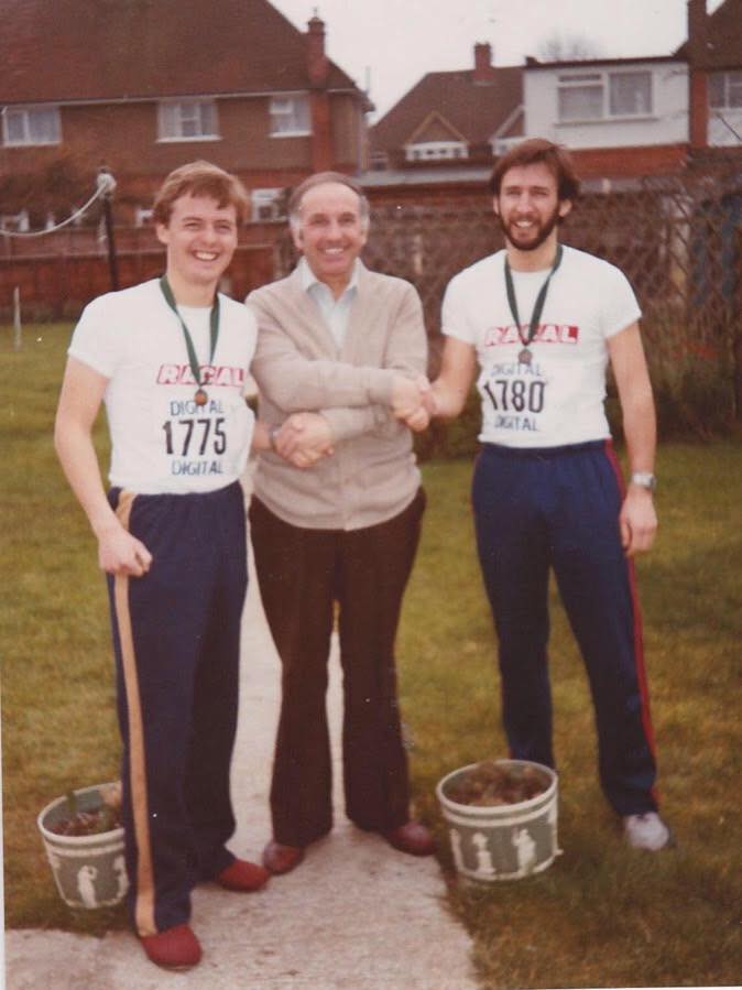 A young Ian and his brother stand in the running t-shirts and with their finishers medals, shaking hands with their father after the first Reading Half Marathon
